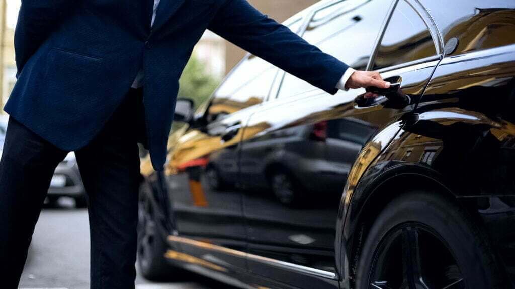Professional chauffeur opening a luxury car door for American Car Service in New Jersey.