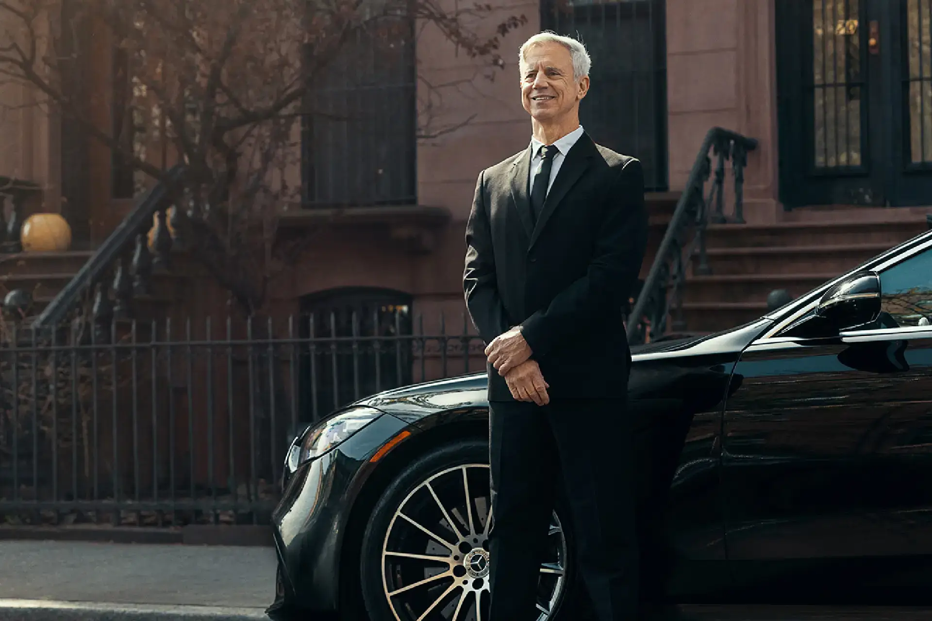 Professional chauffeur standing beside a black luxury car for American Car Service New Jersey.
